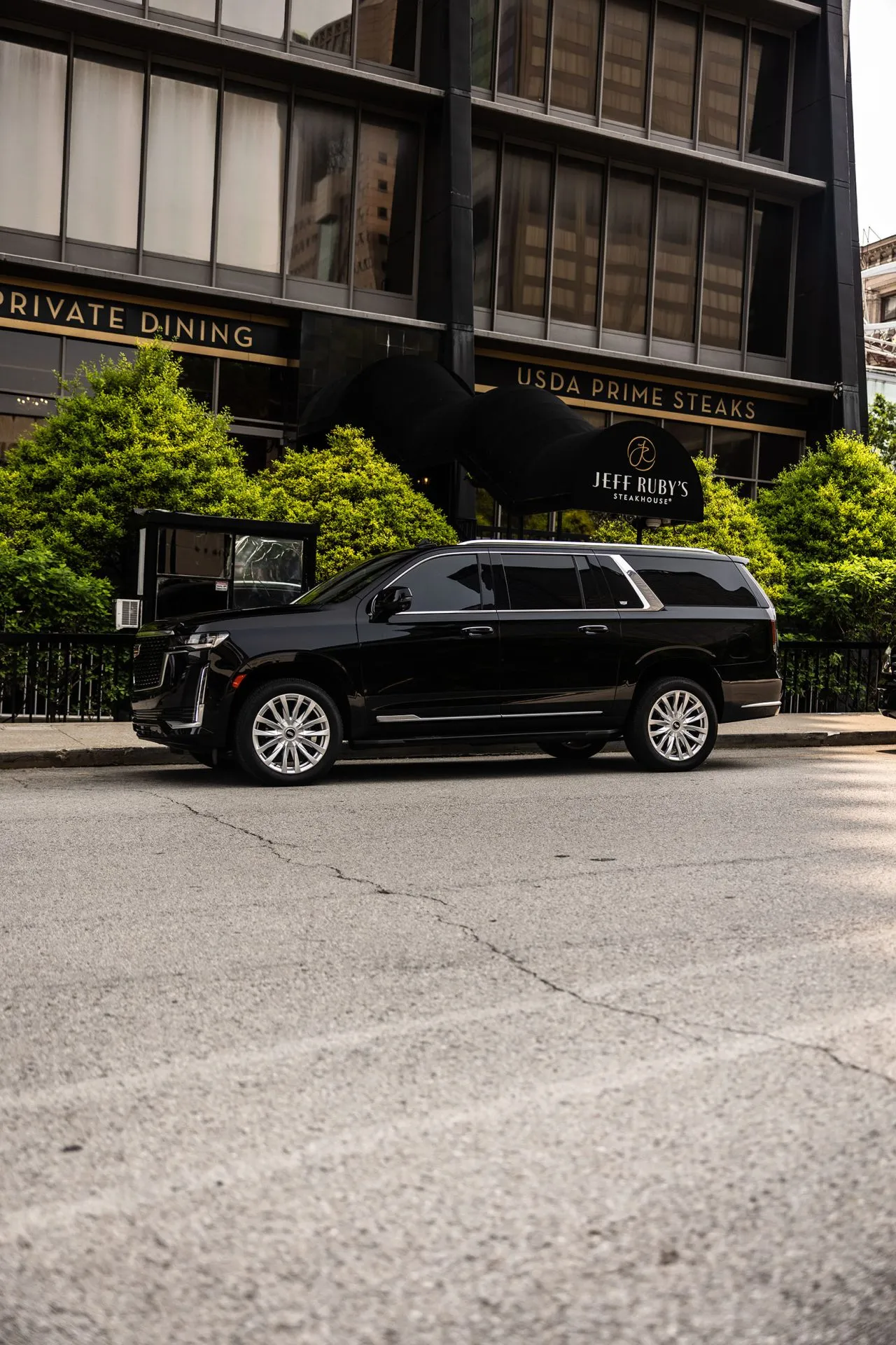 Black Cadillac Escalade ESV parked outside a downtown Louisville steakhouse