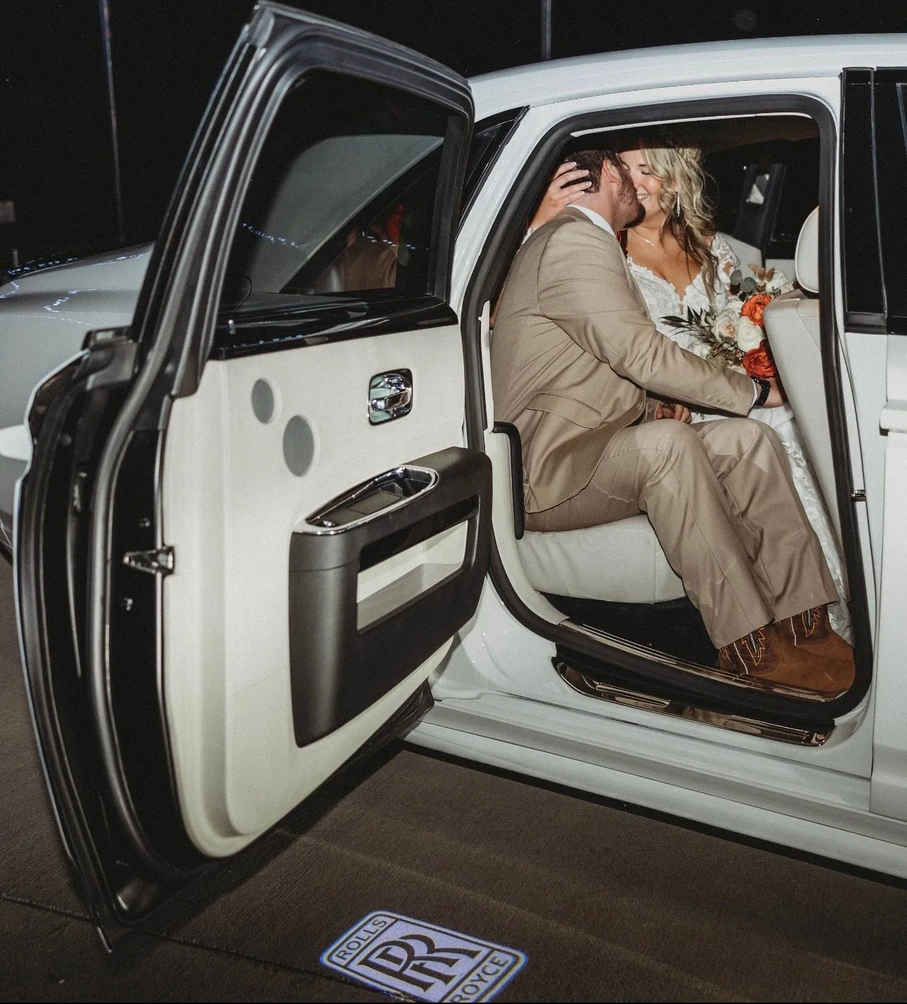Bride and groom seated in the back of a white Rolls-Royce Ghost